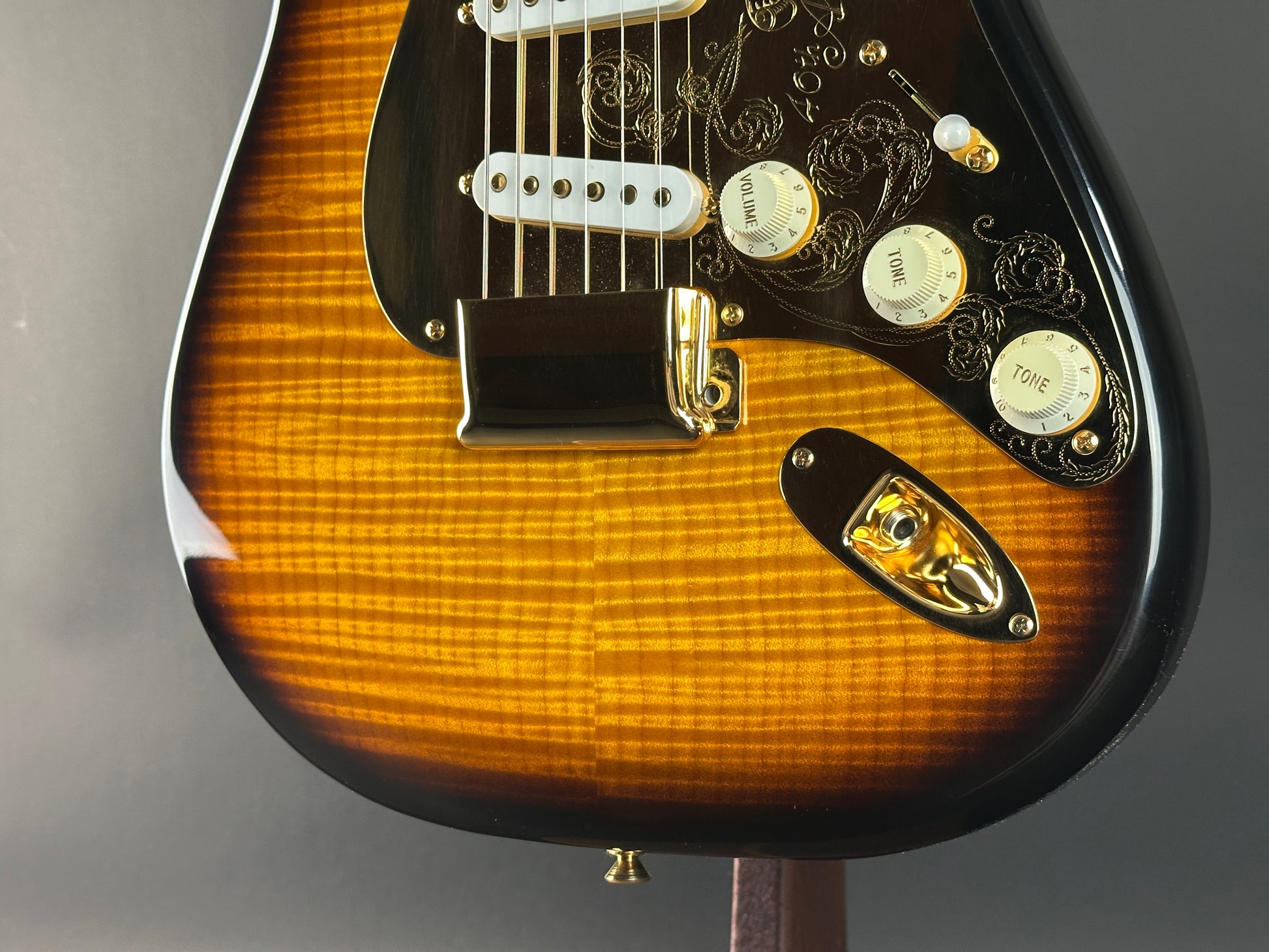 Close-up of a Fender guitar with a sunburst finish on a gray background