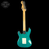 Turquoise electric guitar with a wooden neck on a black background, featuring 'Tone Shop' branding.
