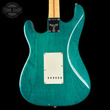 Teal electric guitar with a white pickguard on a black background, featuring the Tone Shop logo.