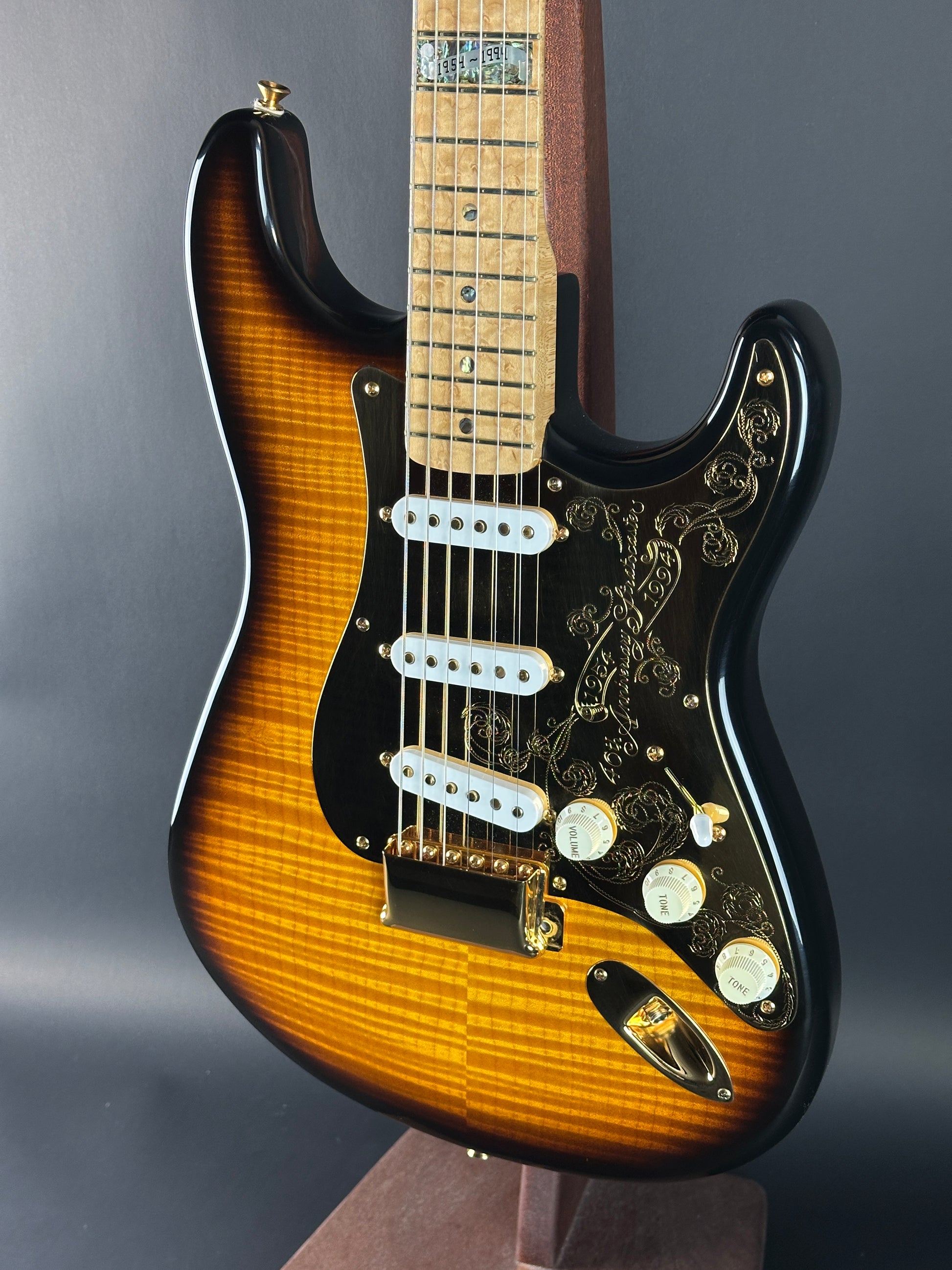 Close-up of a Fender Stratocaster guitar with a sunburst finish on a gray background
