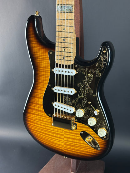Close-up of a Fender Stratocaster guitar with a sunburst finish on a gray background