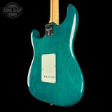 Teal electric guitar with a visible brand logo on a black background
