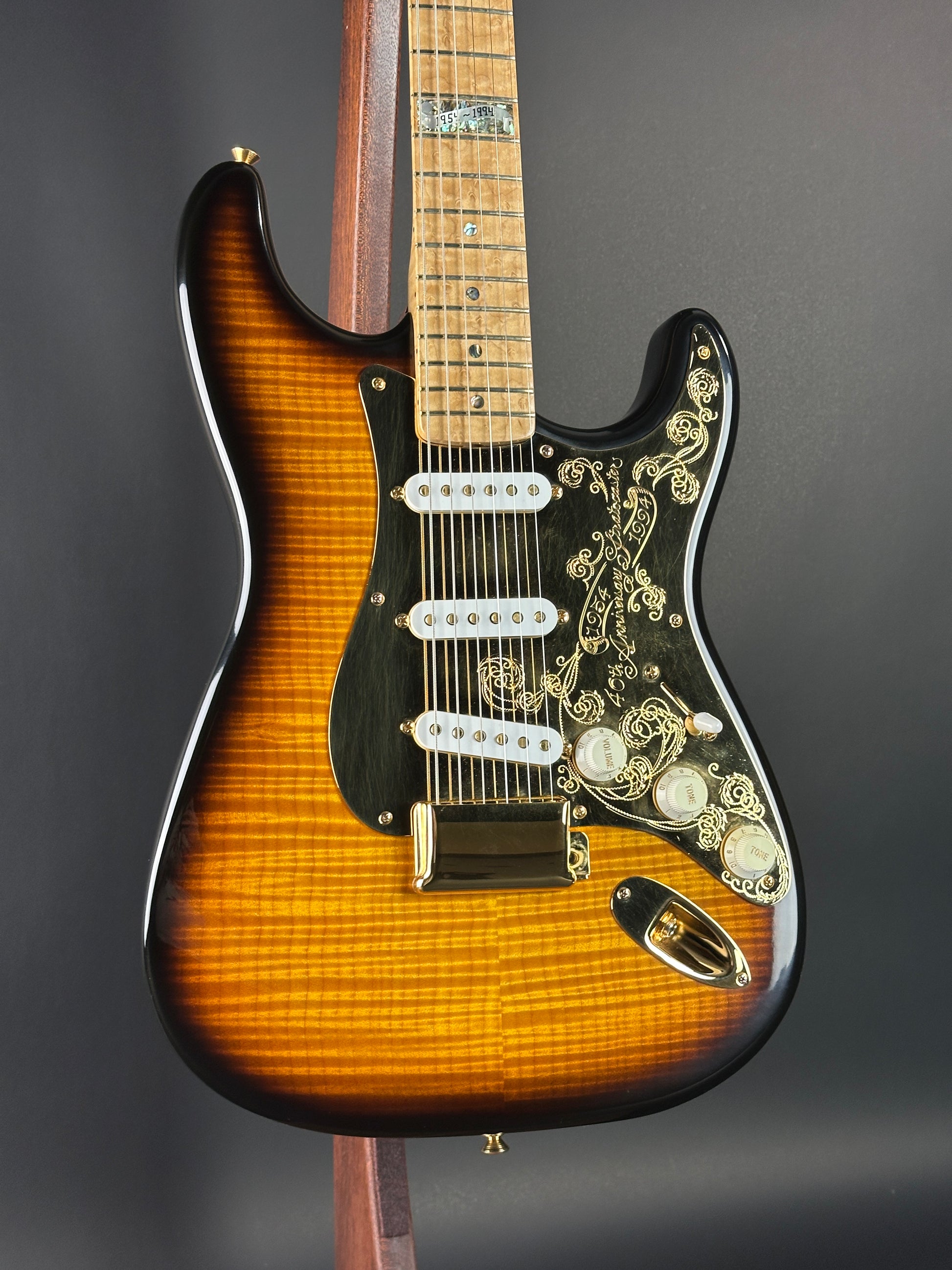 Close-up of a Fender electric guitar with detailed wood finish on a dark background