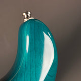 Teal wooden flask with silver cap on a gray background