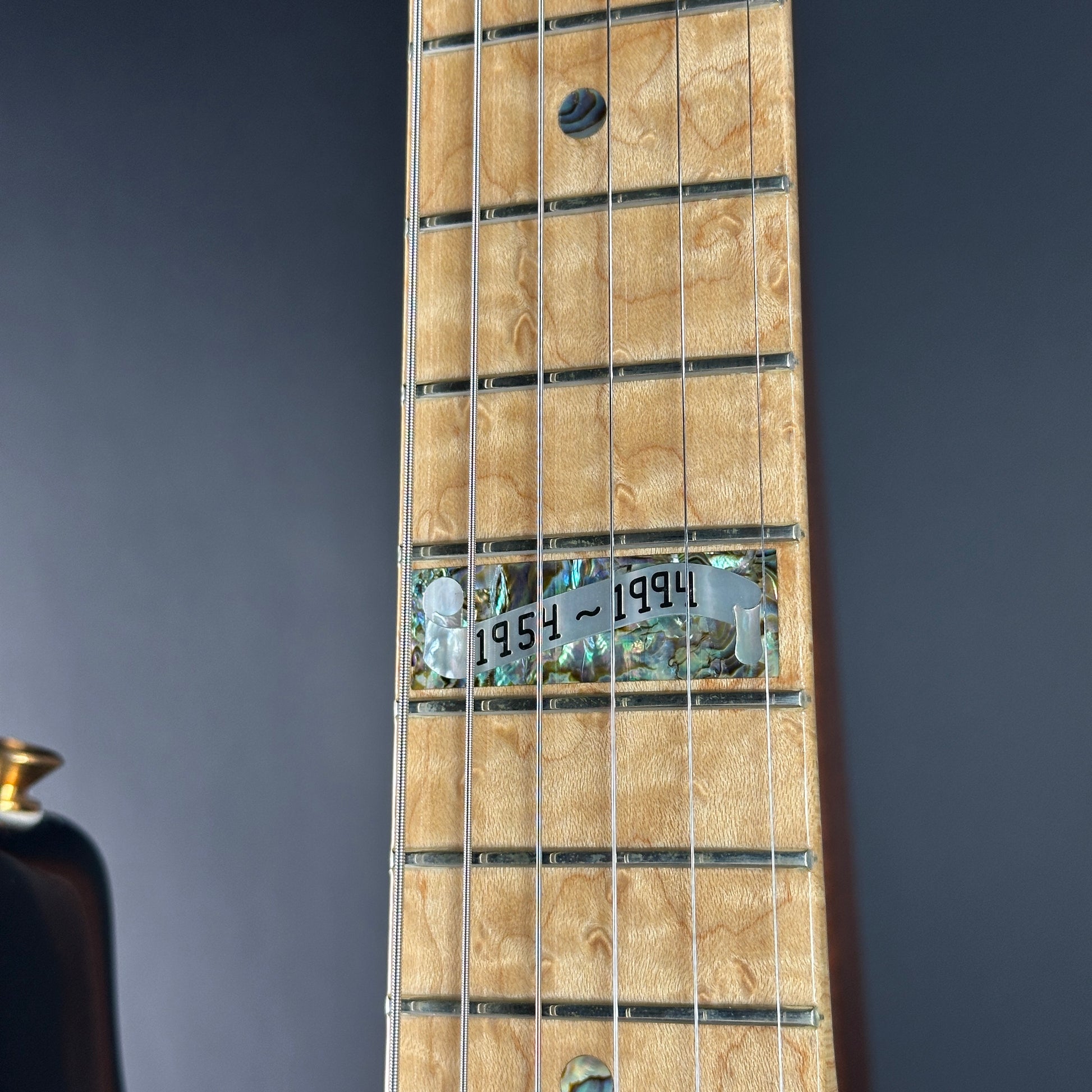 Close-up of a guitar neck with a label on a dark background