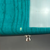 Close-up of a teal wooden product with a metallic base on a gray background
