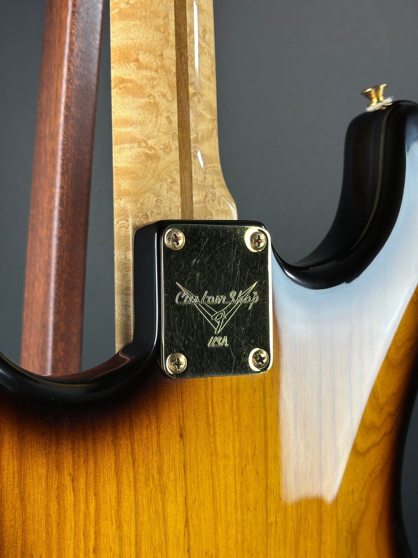 Close-up of a guitar neck with a brand logo on a wooden surface