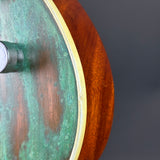 Close-up of a wooden drum with a greenish patina on a dark background