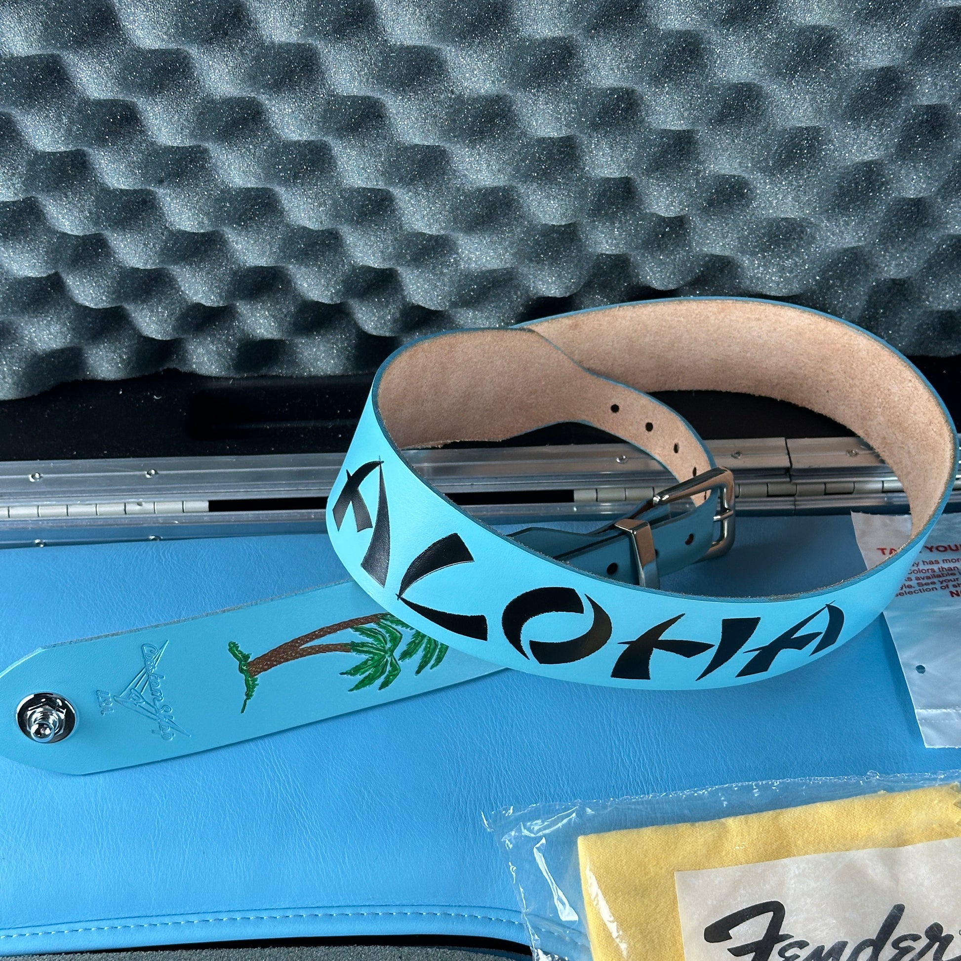 Blue guitar strap with 'Aloha' text on a textured surface