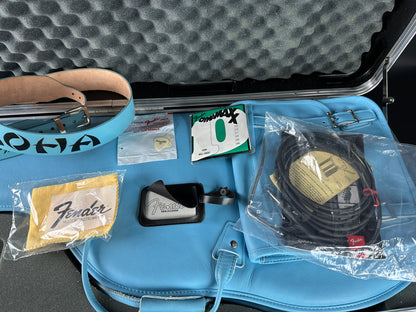 Blue guitar case with Fender accessories including a cable, strap, and cleaning cloth.