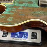 Acoustic guitar on a digital scale displaying weight