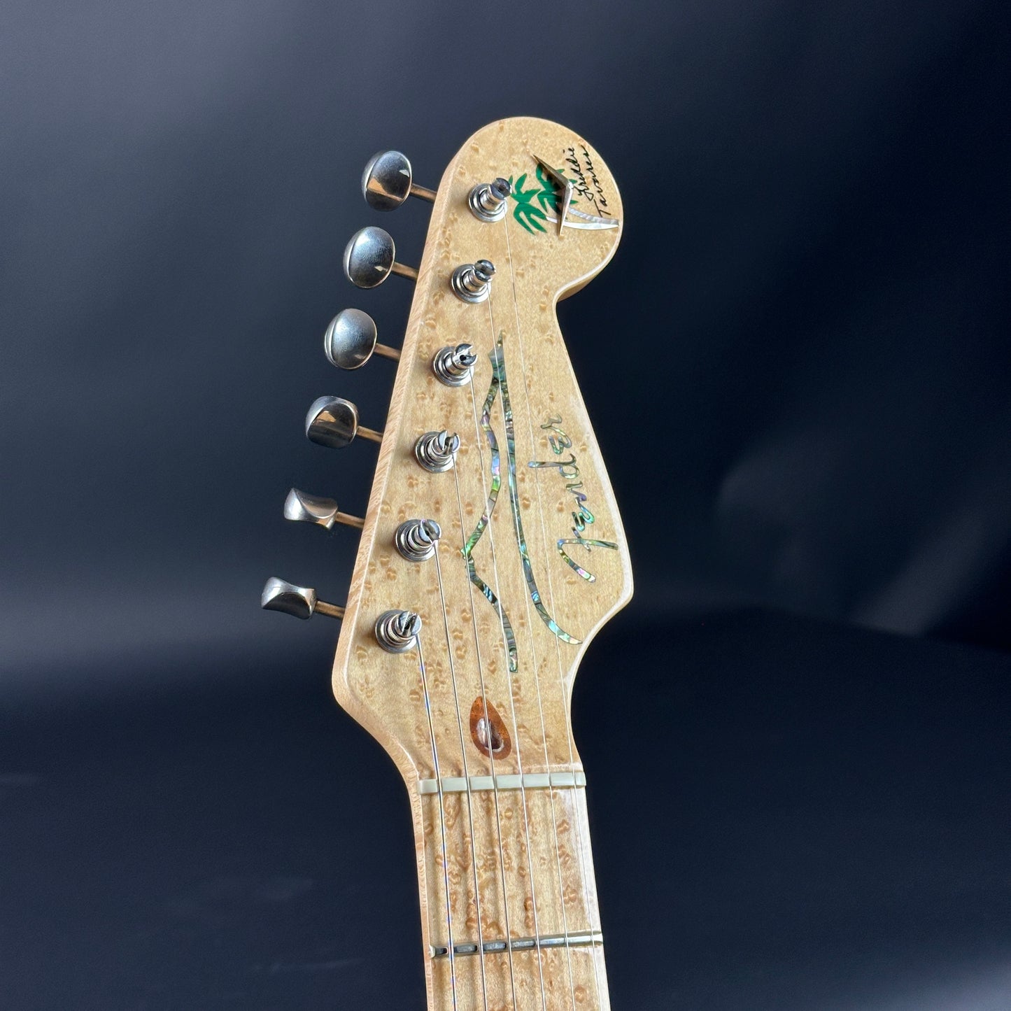 Close-up of a guitar headstock with Fender logo on a dark background