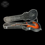 Guitar in a hard-shell case with 'Tone Shop' logo in the corner.