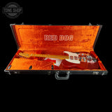 A red electric guitar with a white pickguard displayed inside an open black hard case with bright orange velvet lining. The inside lid features the words 'RED DOG' in white.