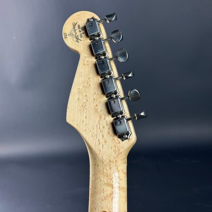 Guitar headstock with tuning pegs on a dark background