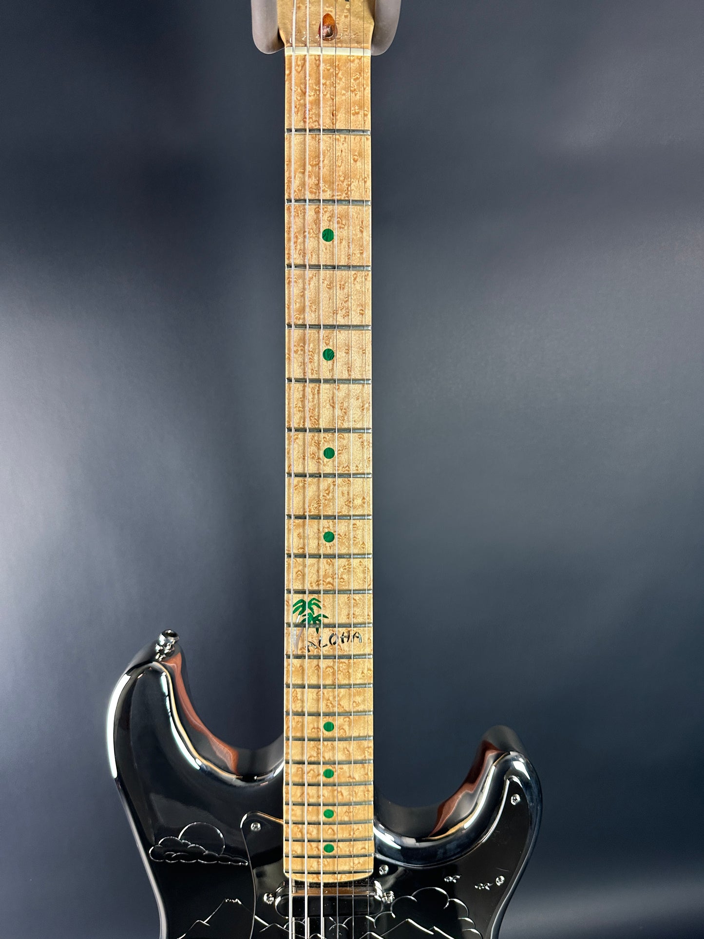 Electric guitar neck with brand logo on a dark background