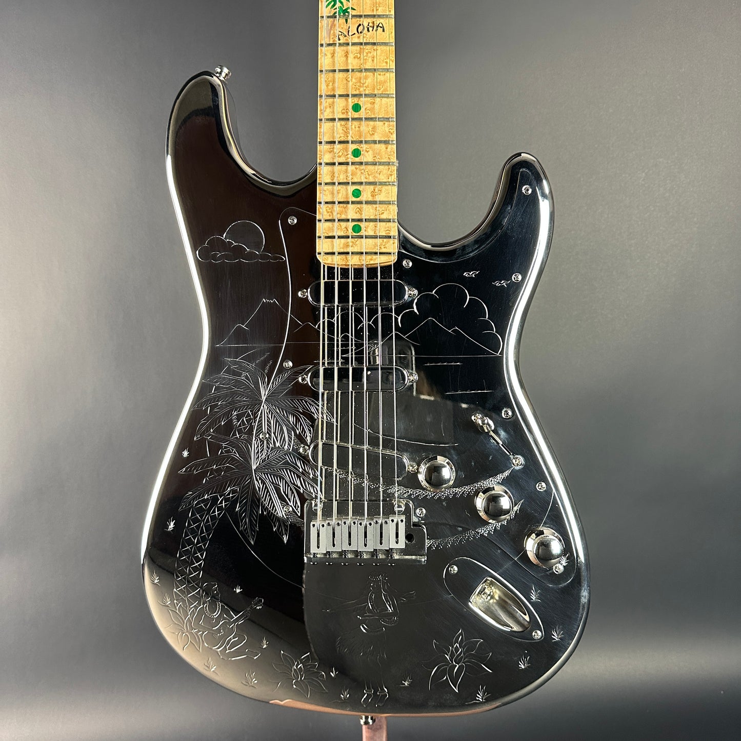 Black electric guitar with engraved design on a gray background