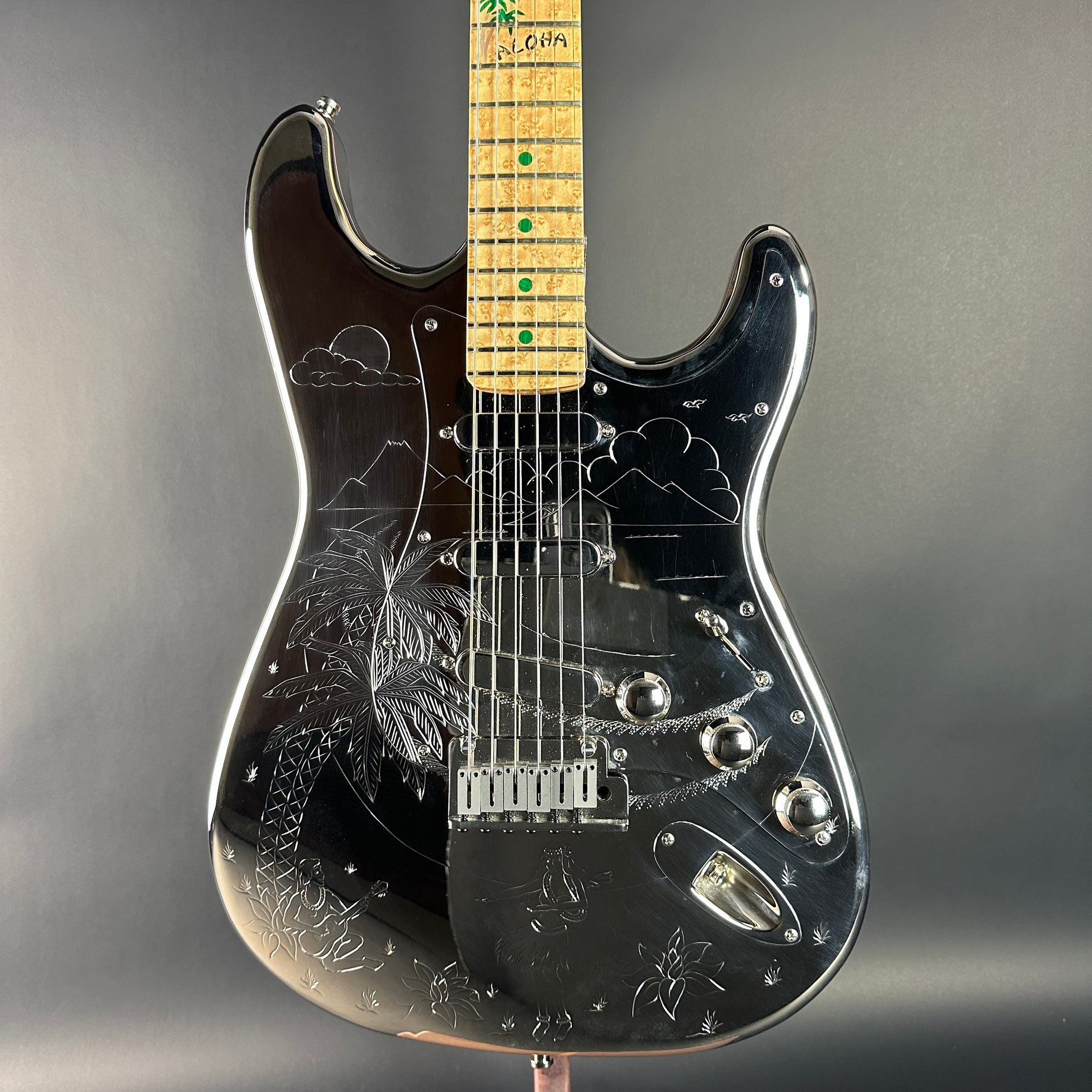 Black electric guitar with engraved design on a gray background