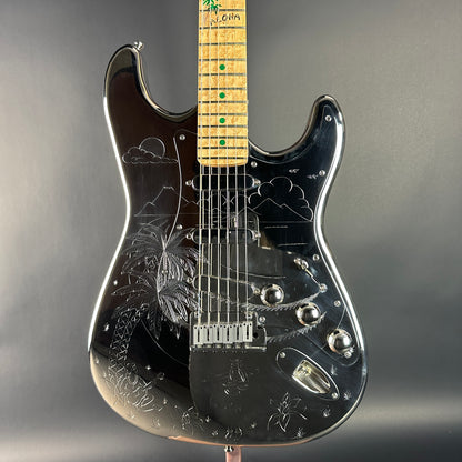 Black electric guitar with engraved design on a gray background