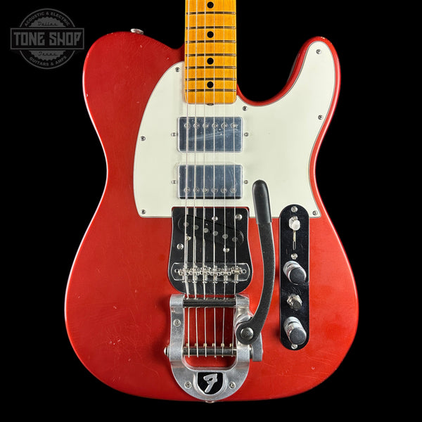 A red Telecaster-style electric guitar with a cream pickguard, maple neck, black control plate, and silver tremolo hardware, photographed against a black background. A Tone Shop watermark is visible in the top-left corner.