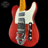A red electric guitar with a white pickguard, maple neck, and black bridge, shown against a black background with a Tone Shop watermark in the top left corner.