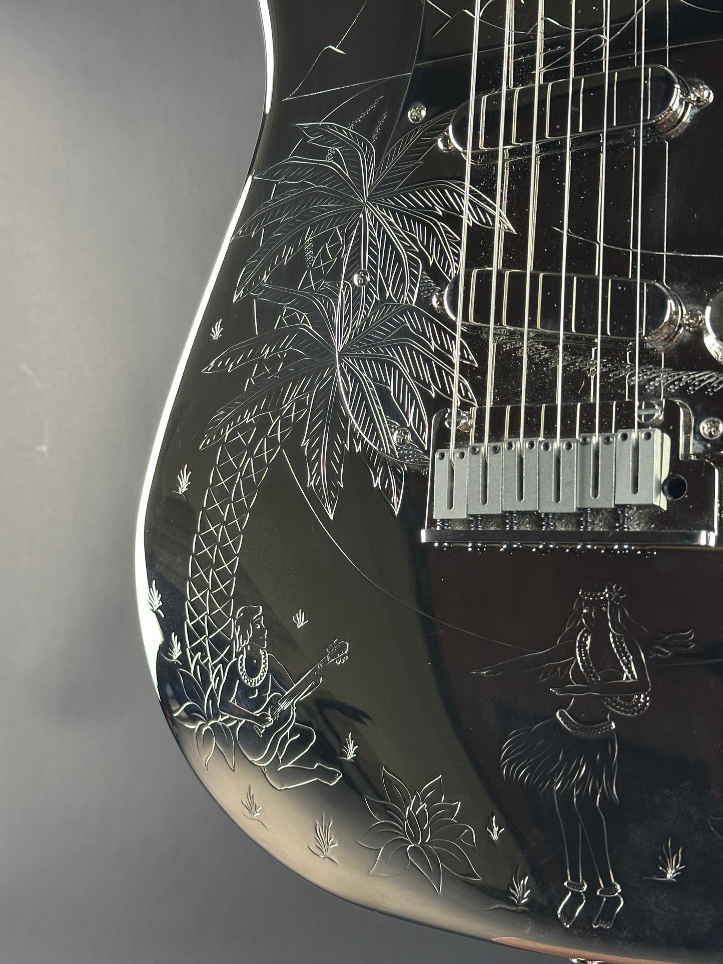 Close-up of a black electric guitar with intricate white engravings on the body.