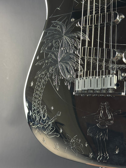 Close-up of a black electric guitar with intricate white engravings on the body.