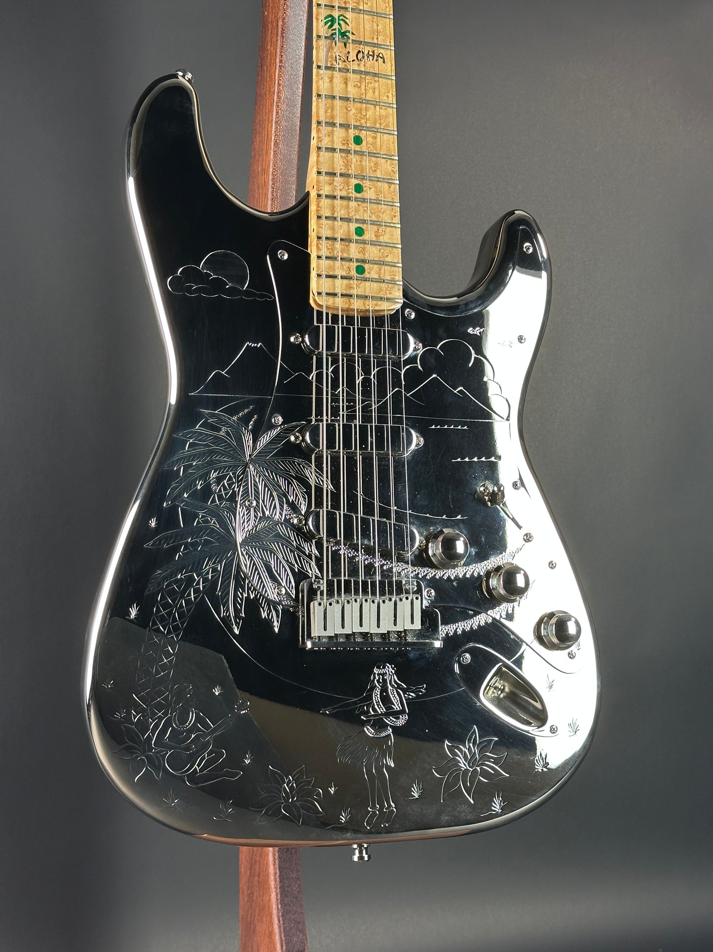 Close-up of a black electric guitar with engraved designs on a dark background