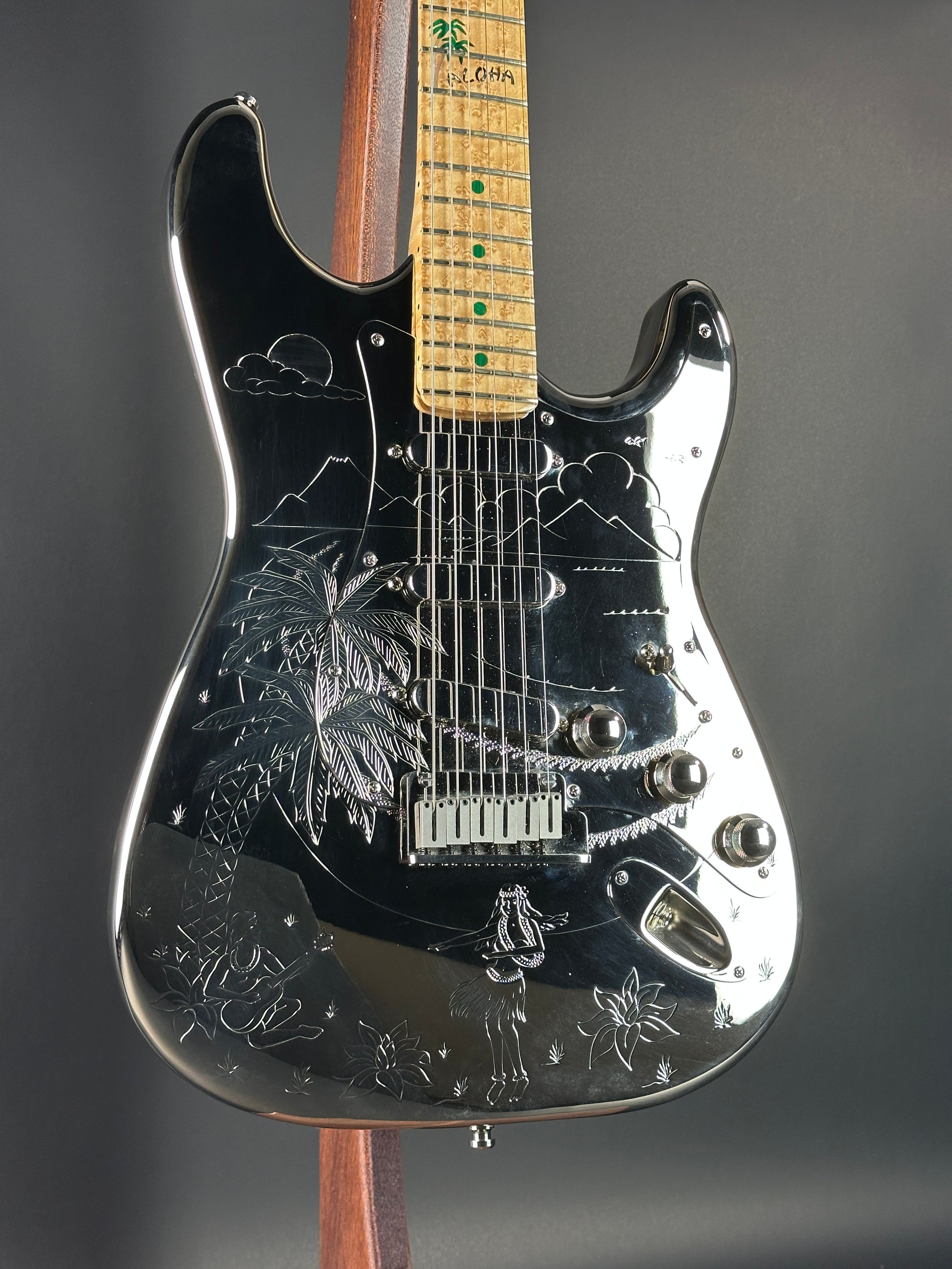 Close-up of a black electric guitar with engraved designs on a dark background
