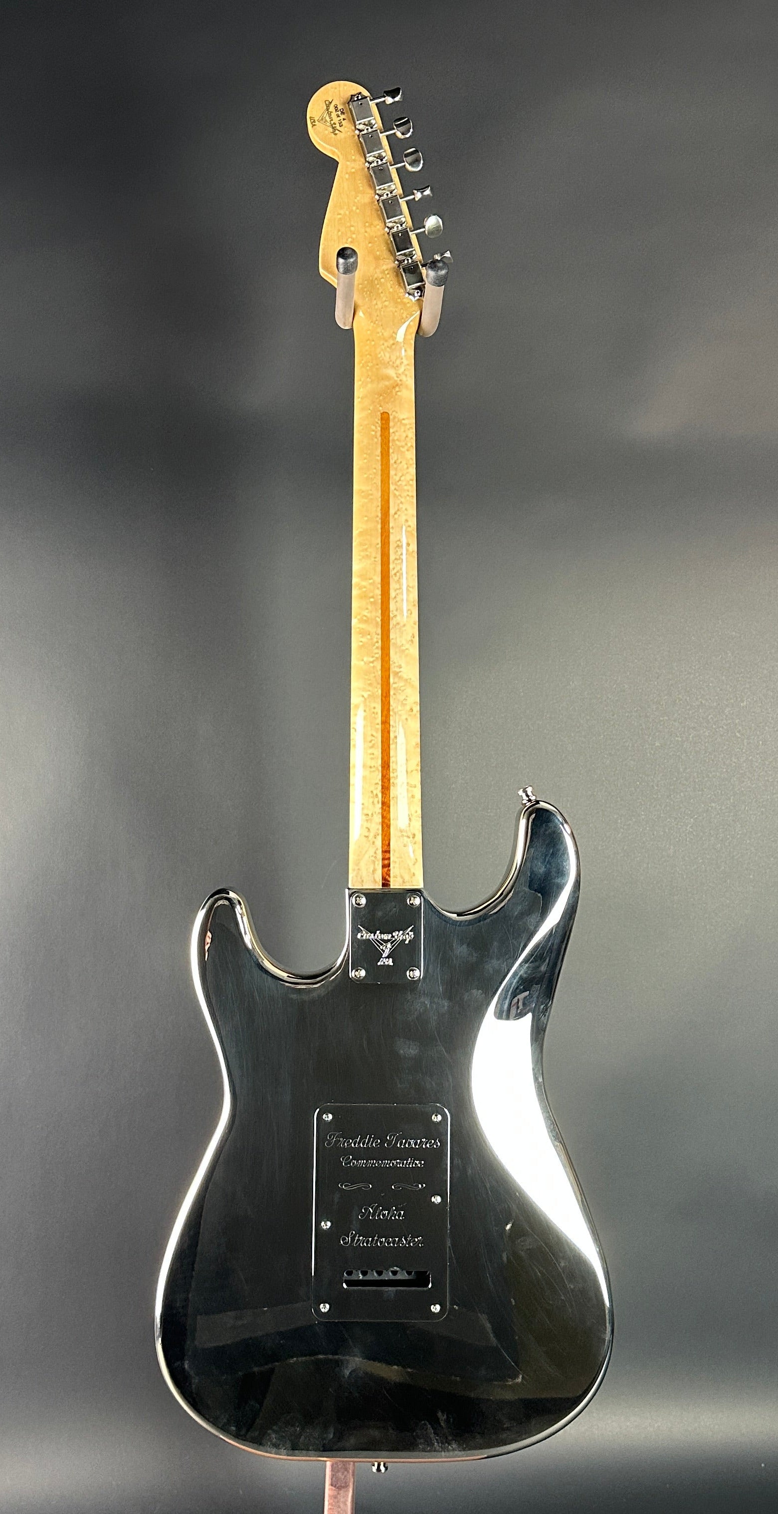 Black electric guitar on a reflective gray surface