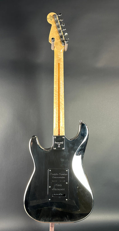 Black electric guitar on a reflective gray surface