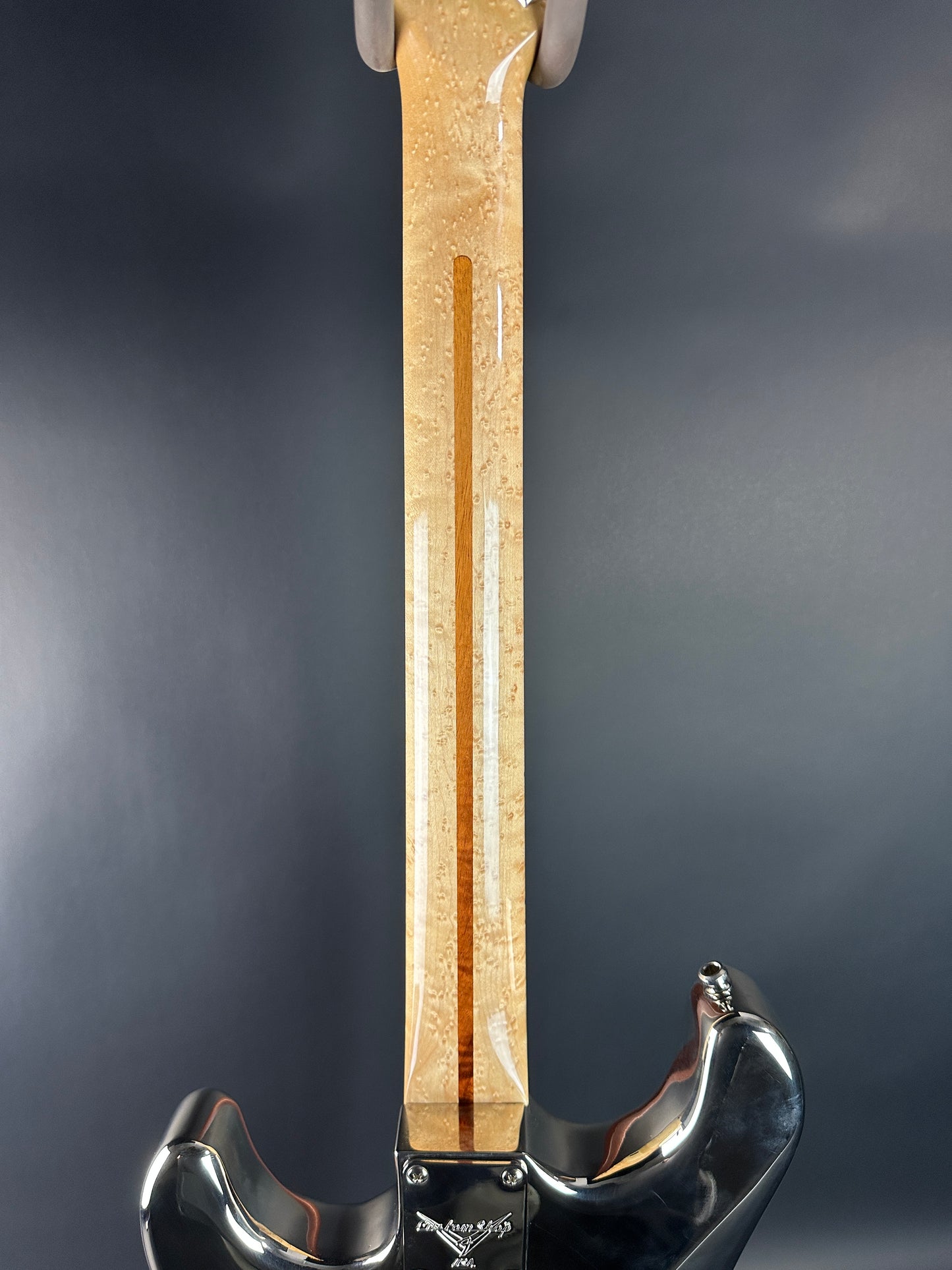 Close-up of a guitar neck with a pickguard on a dark background