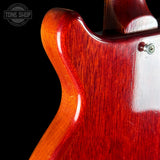 Close-up of a red electric guitar's body with a visible brand logo in the corner.