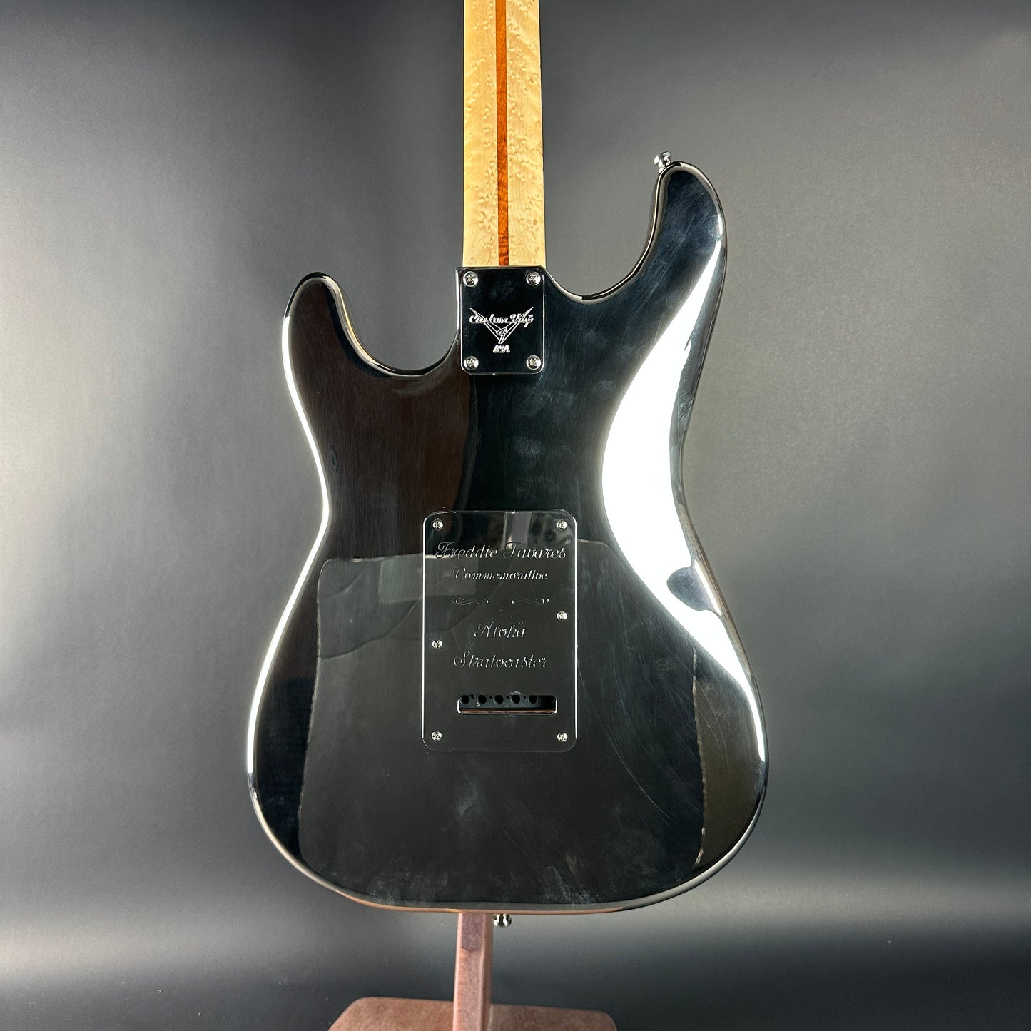 Black electric guitar on a stand with a gray background