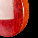 Close-up of a red and white object with a textured surface on a black background