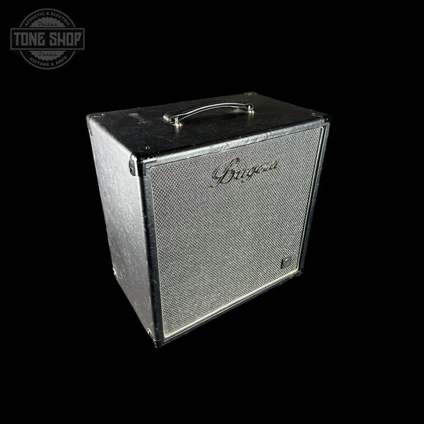A vintage black guitar amplifier cabinet with a silver-gray textured grille and a silver handle, shown against a solid black background. The brand name 'Bugera' is visible on the grille.
