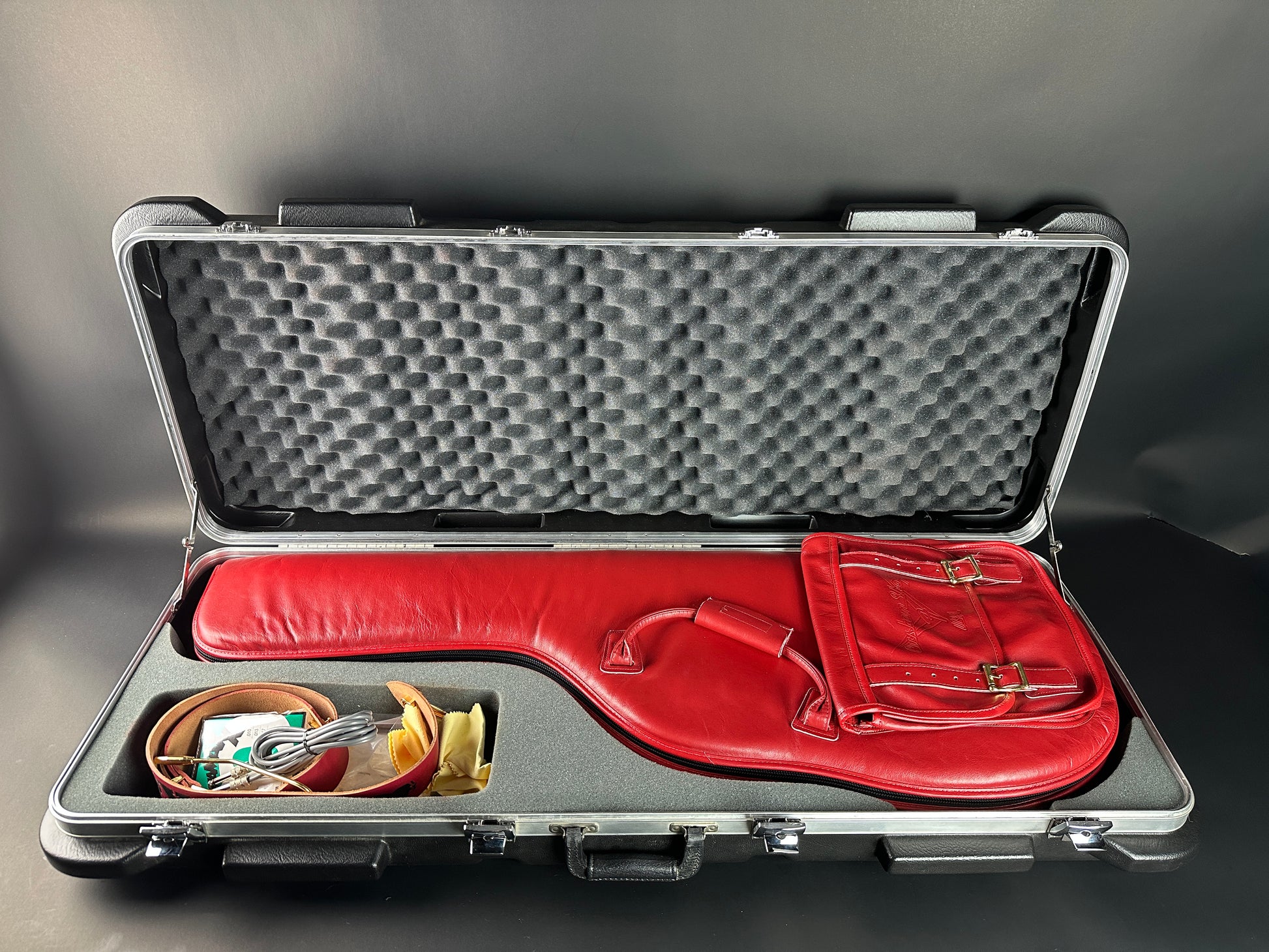 Red guitar case with accessories inside on a gray background
