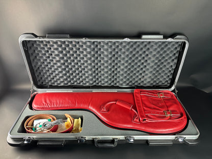 Red guitar case with accessories inside on a gray background