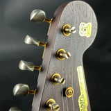 Close-up of a guitar headstock with tuning pegs and brand name on a dark background
