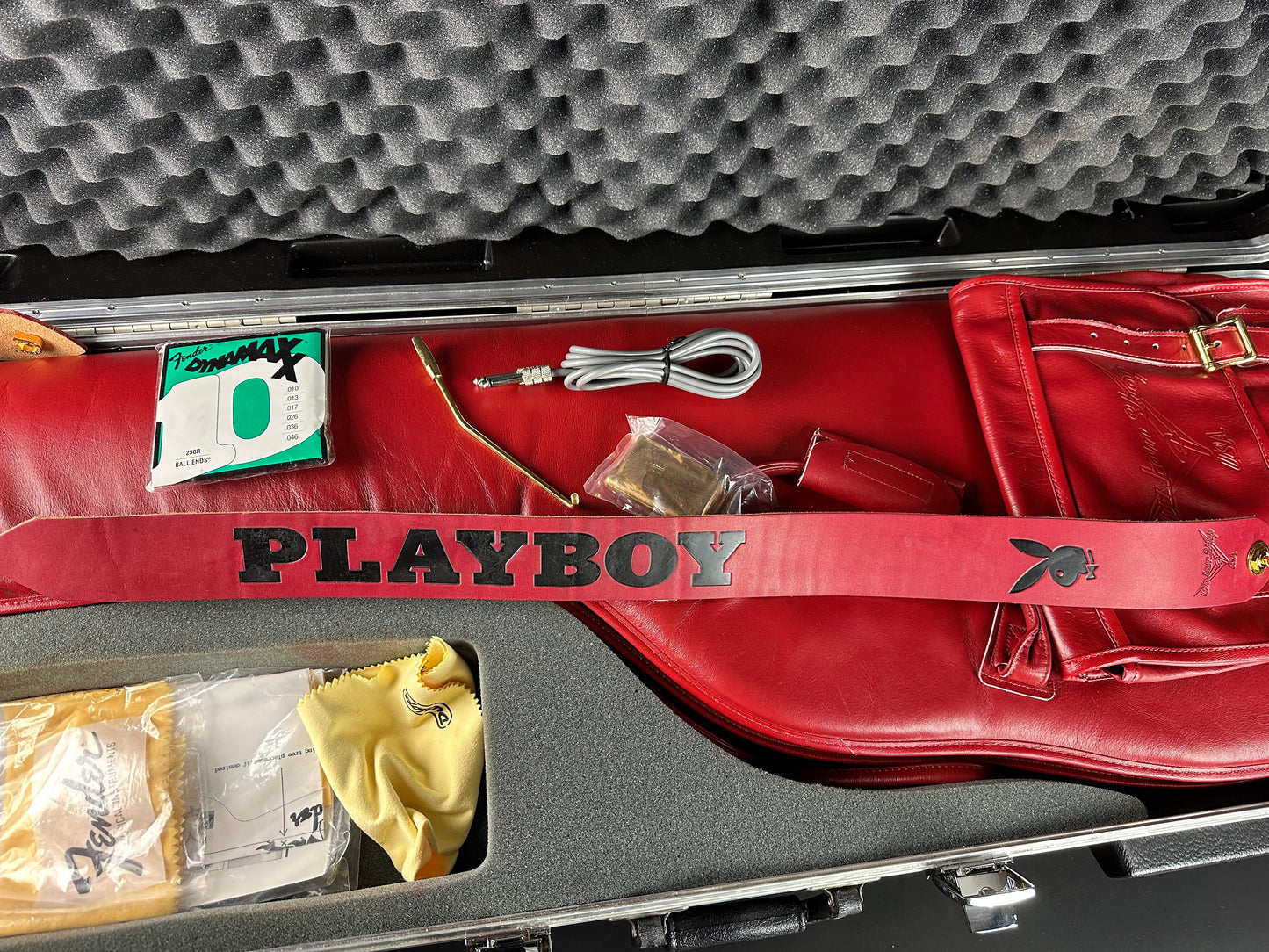 Red guitar case with 'Playboy' branding on a gray textured background