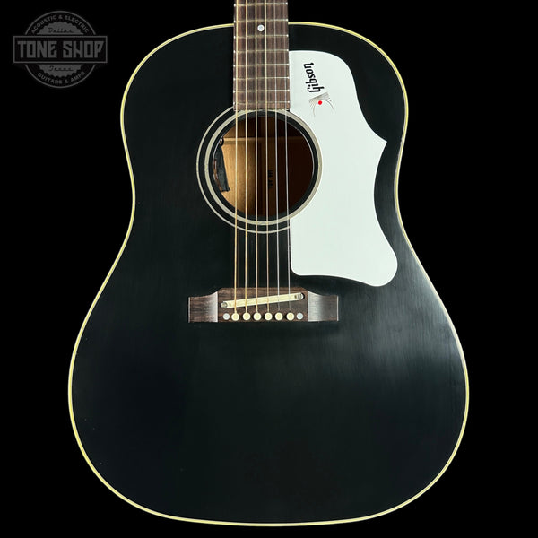 Black acoustic guitar with a visible brand logo on a black background