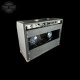 A vintage black guitar amplifier with a textured cabinet, chrome dials, and visible internal speakers, shown on a solid black background with a Tone Shop watermark in the top-left corner.