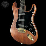 Wooden electric guitar with a black pickguard on a black background, featuring the Tone Shop logo.