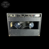A vintage black guitar amplifier head with an open front cover, showing two large blue and black speakers inside and a control panel on top. The Tone Shop logo is visible in the top left corner.