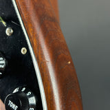Close-up of a guitar's wood grain and control knobs on a gray background