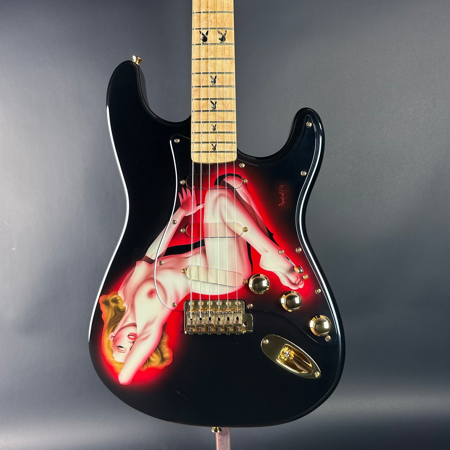 Black electric guitar with a colorful design on the body against a gray background