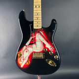 Black electric guitar with a colorful design on the body against a gray background