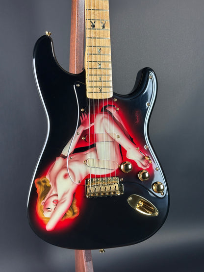 Guitar with a graphic design of a nude figure on a dark background