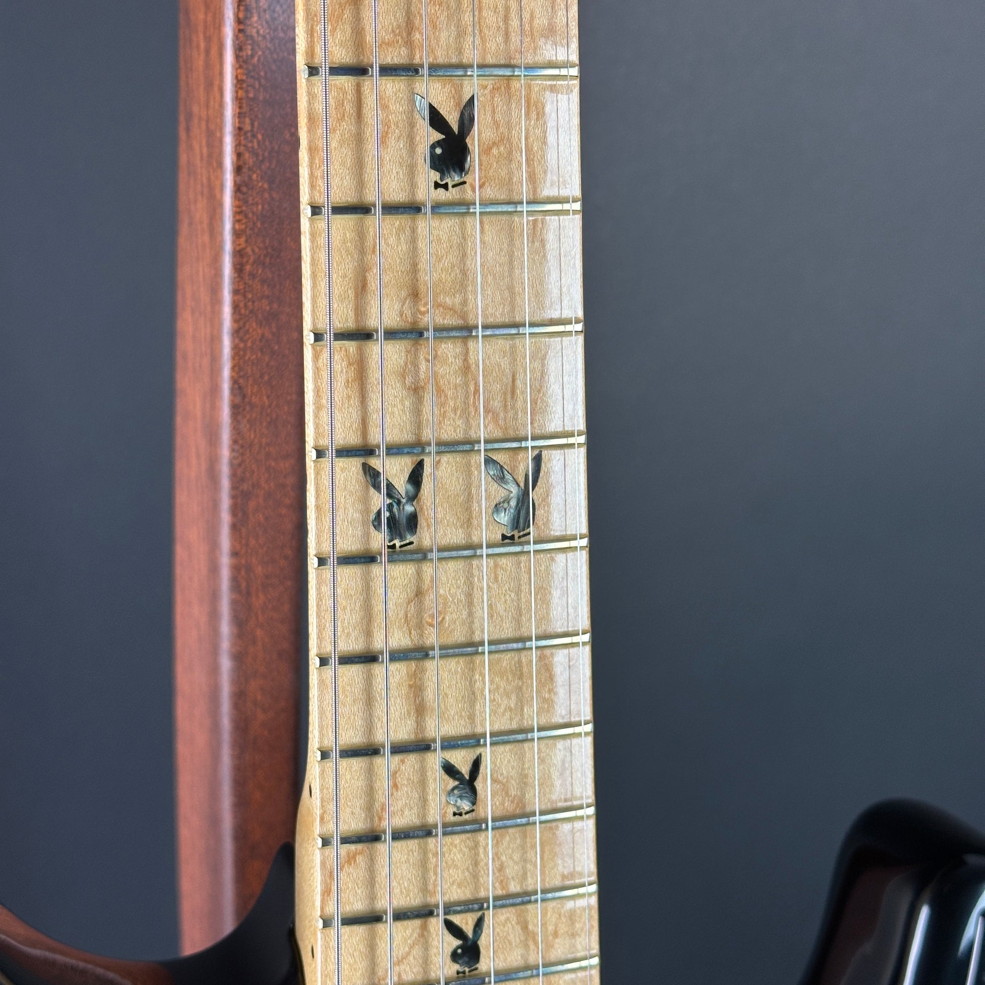 Close-up of a guitar neck with decorative stickers on the fretboard against a dark background