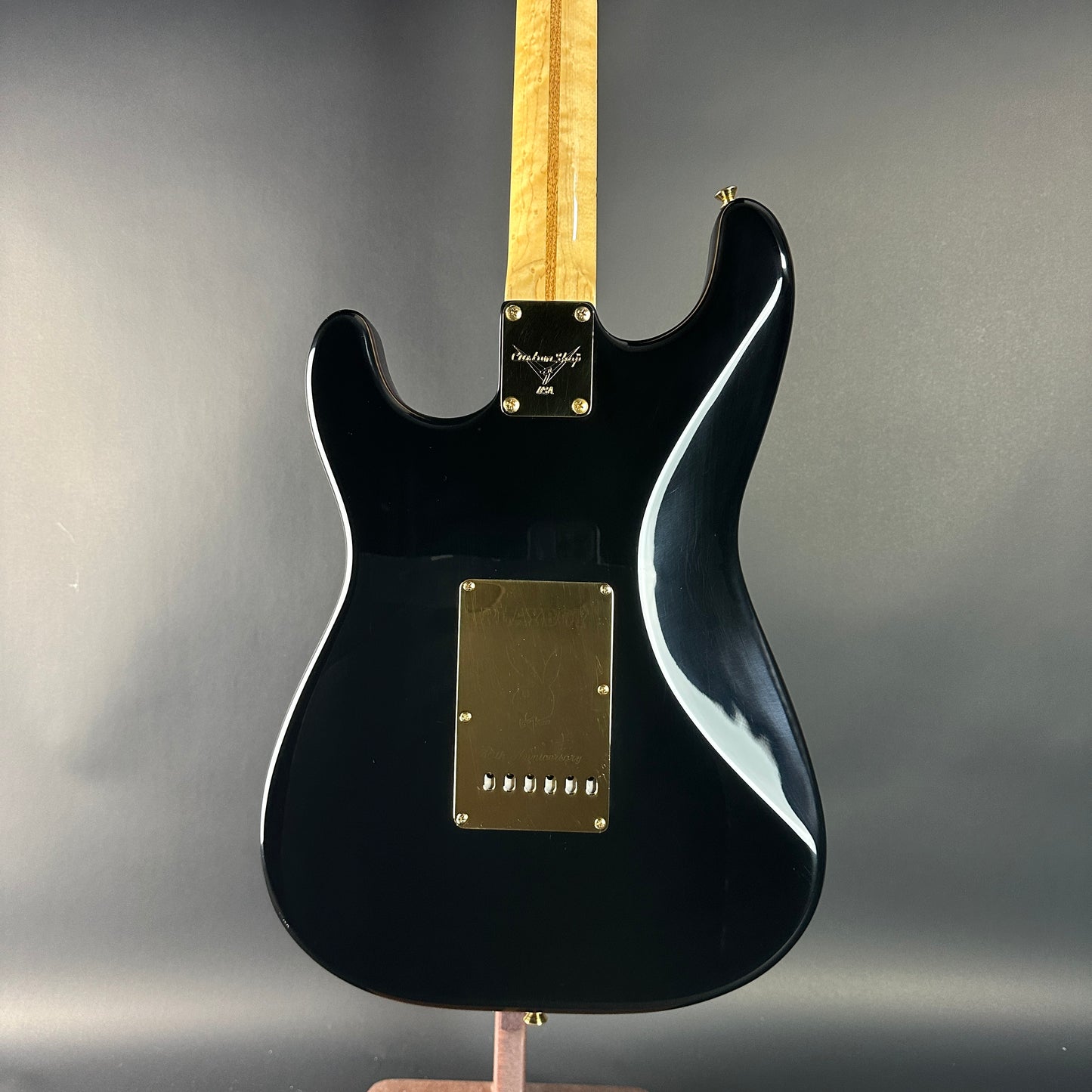 Black electric guitar with a blonde fretboard on a gray background